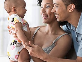 Smiling mom and dad holding their 4 month old baby