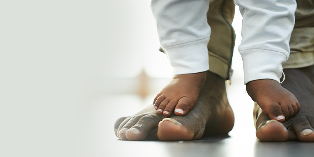 Baby walking on dad's feet
