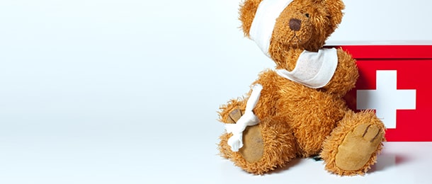 Bandaged teddy next to a first-aid box