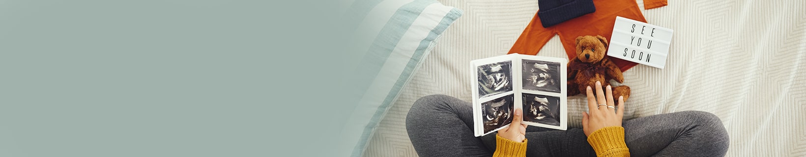 Woman looking at ultrasound photos and a teddy bear