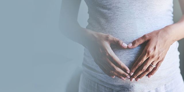 Week 18 pregnant woman holding her hands over her belly